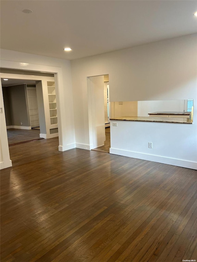 unfurnished living room featuring dark hardwood / wood-style floors and a baseboard heating unit