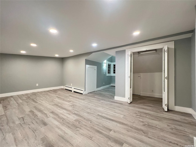 basement featuring baseboard heating and light hardwood / wood-style flooring