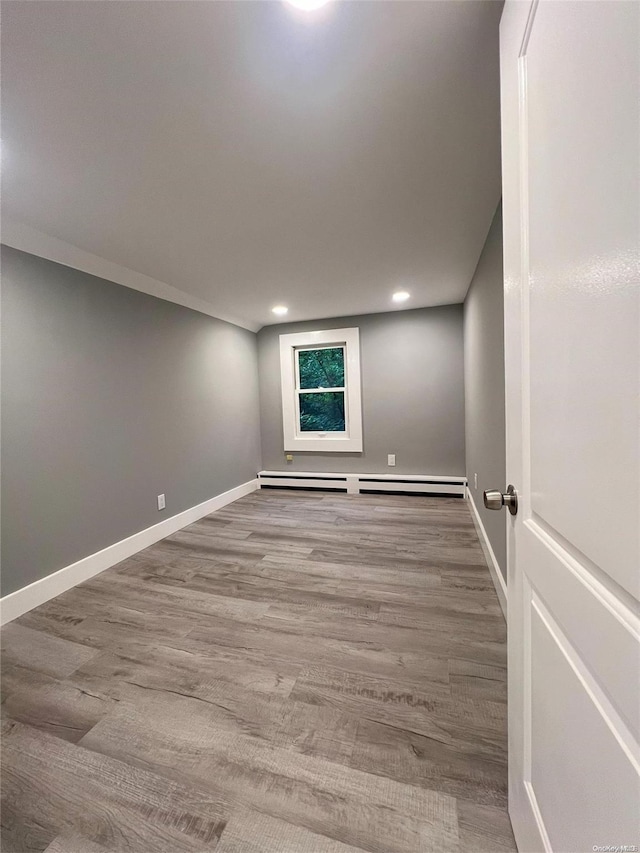 empty room with light hardwood / wood-style flooring and a baseboard heating unit