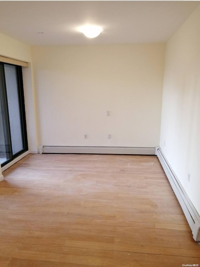 empty room featuring light wood-type flooring and a baseboard heating unit