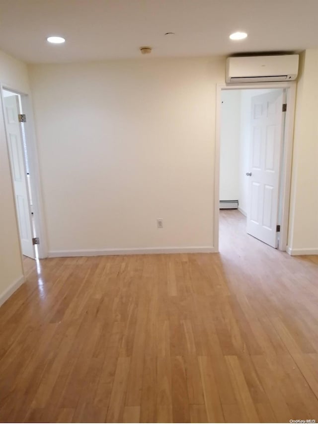 empty room featuring a baseboard radiator, light hardwood / wood-style flooring, and a wall mounted AC