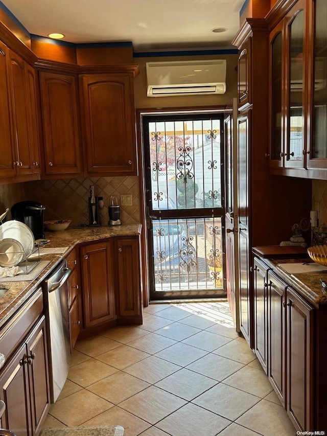 kitchen with a wall mounted air conditioner, stone counters, stainless steel dishwasher, light tile patterned floors, and tasteful backsplash