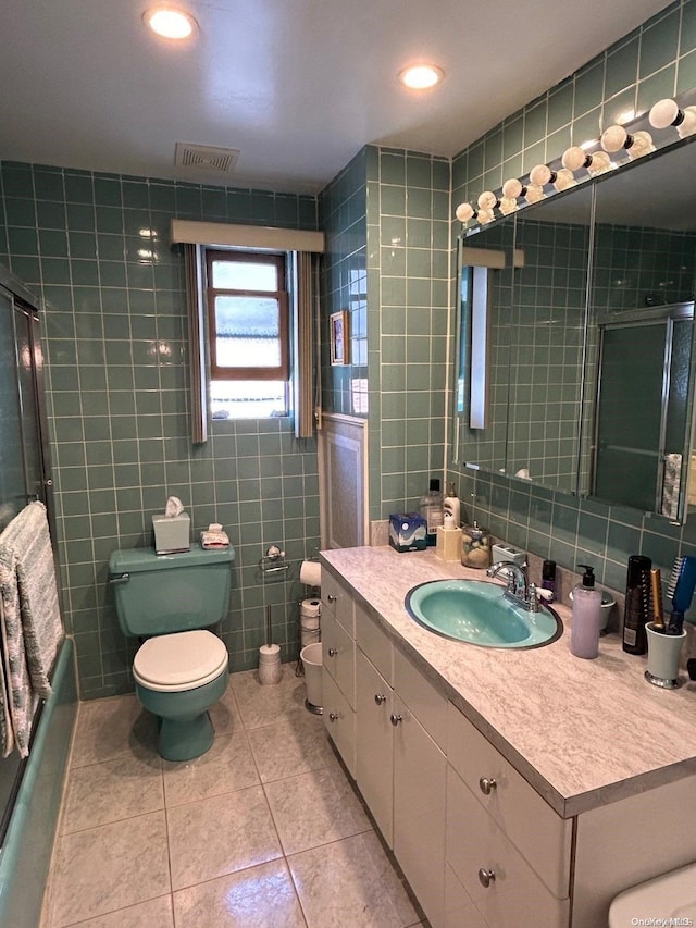 bathroom featuring tile patterned flooring, vanity, toilet, and tile walls