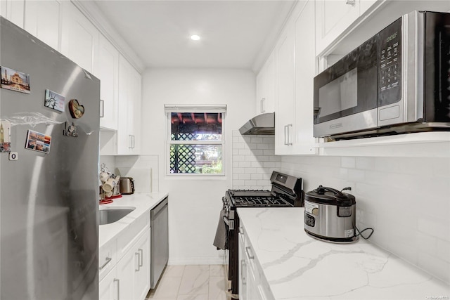 kitchen with light stone countertops, appliances with stainless steel finishes, tasteful backsplash, and white cabinetry