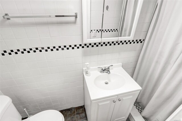 bathroom with tile patterned floors, vanity, toilet, and tile walls