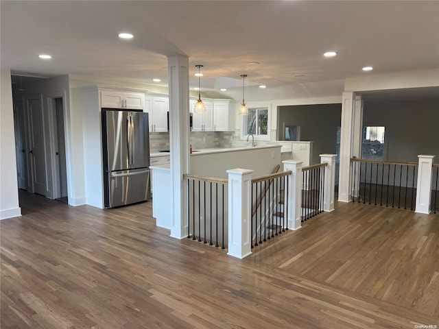 kitchen featuring white cabinets, stainless steel fridge, dark hardwood / wood-style flooring, and kitchen peninsula