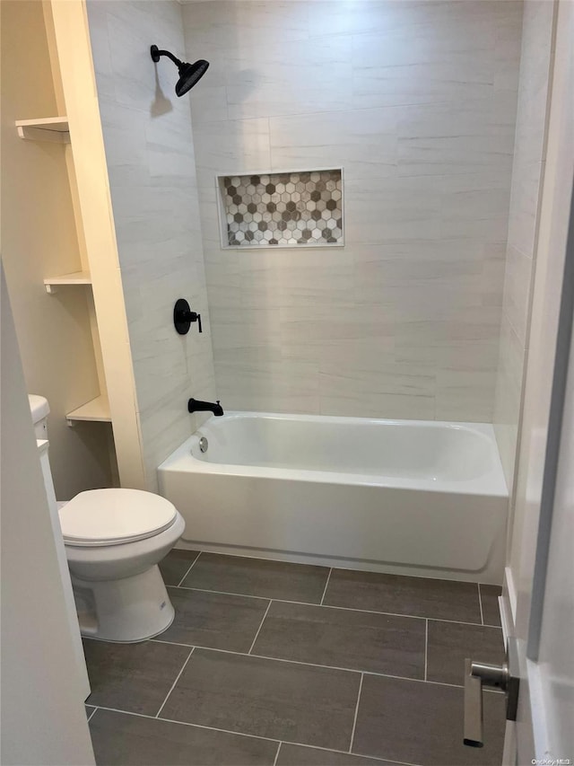 bathroom with tile patterned flooring, toilet, and tiled shower / bath