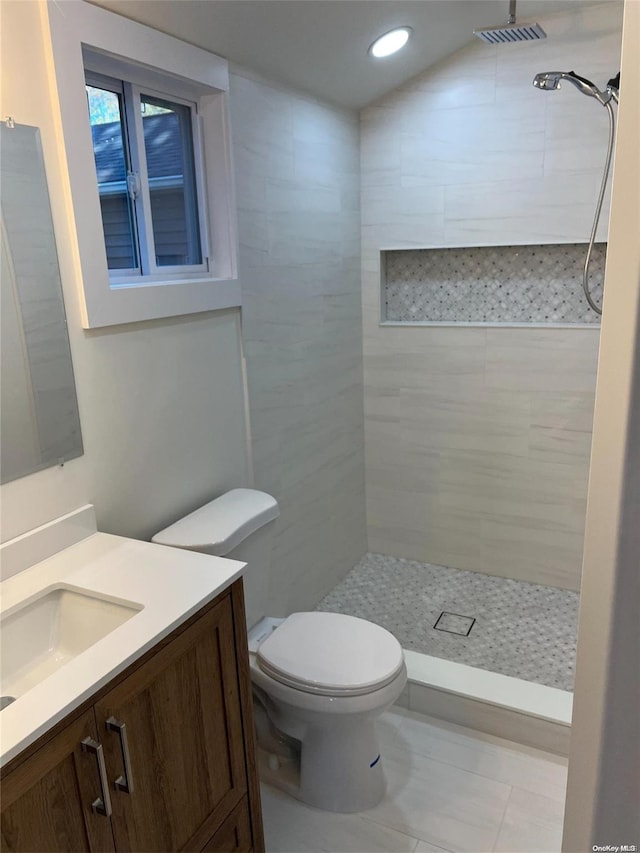 bathroom with tiled shower, vanity, and toilet