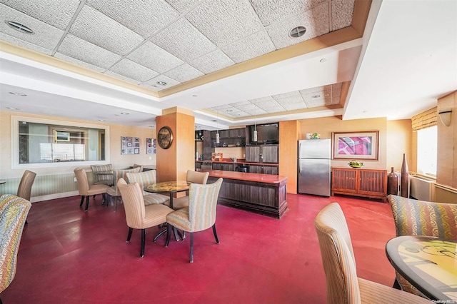 dining space featuring concrete floors, a tray ceiling, and a drop ceiling