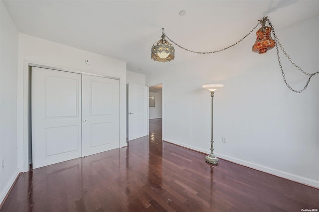 unfurnished bedroom with dark wood-type flooring and a closet