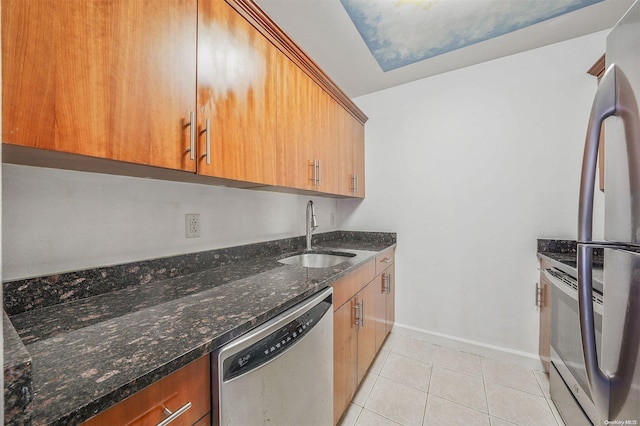 kitchen featuring light tile patterned flooring, appliances with stainless steel finishes, dark stone countertops, and sink