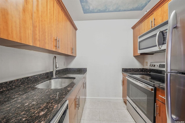 kitchen featuring light tile patterned flooring, sink, stainless steel appliances, and dark stone counters