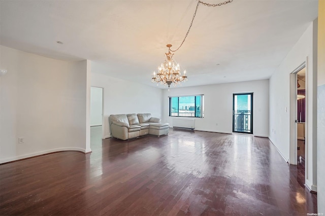 unfurnished living room featuring a chandelier and dark wood-type flooring