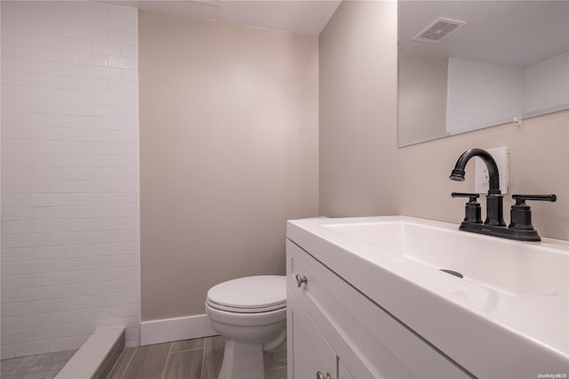 bathroom with walk in shower, vanity, and toilet