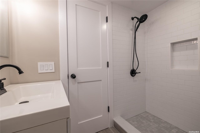 bathroom with a tile shower and vanity