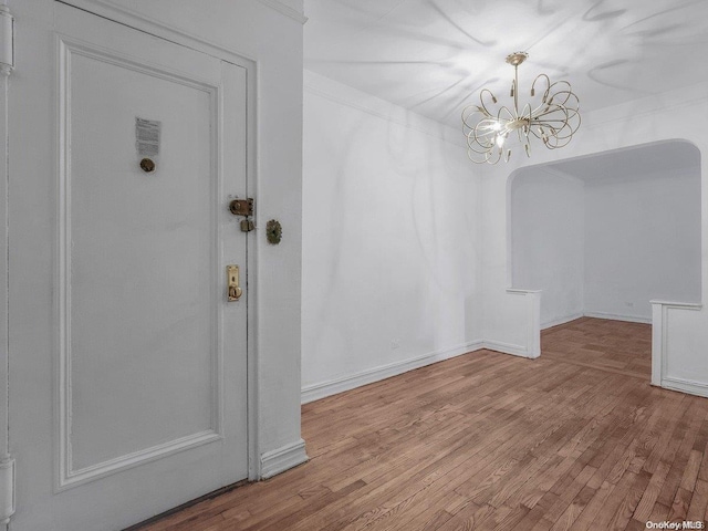 unfurnished dining area with light wood-type flooring, an inviting chandelier, and crown molding