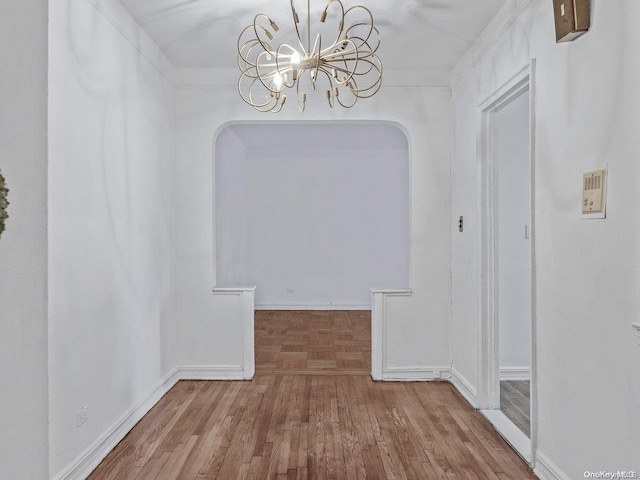 interior space with wood-type flooring, crown molding, and a notable chandelier