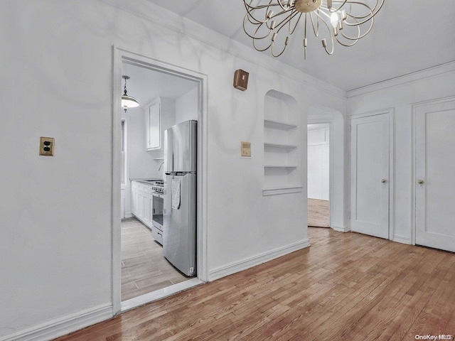 hall with ornamental molding, a chandelier, and light wood-type flooring