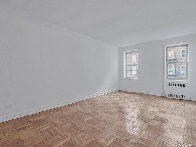 unfurnished room featuring radiator heating unit and light parquet floors