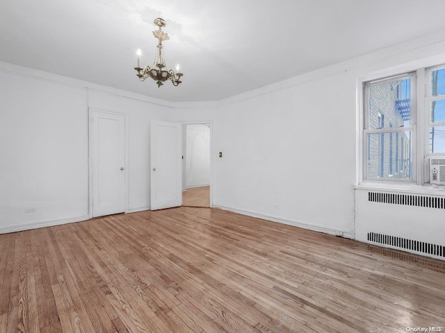 unfurnished bedroom featuring a notable chandelier, light wood-type flooring, radiator heating unit, and ornamental molding