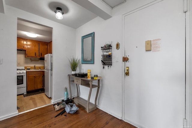 kitchen featuring decorative backsplash, hardwood / wood-style floors, and white appliances