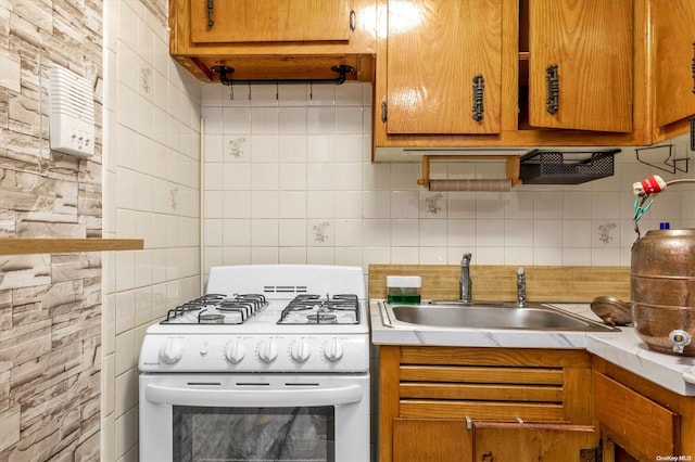 kitchen featuring white range with gas stovetop, tasteful backsplash, and sink