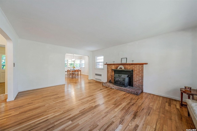 unfurnished living room with a fireplace, radiator heating unit, and light wood-type flooring