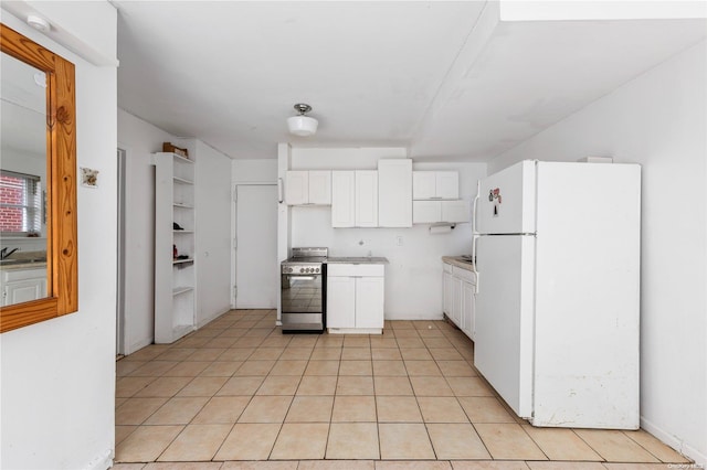 kitchen with sink, light tile patterned floors, white refrigerator, stainless steel range oven, and white cabinets