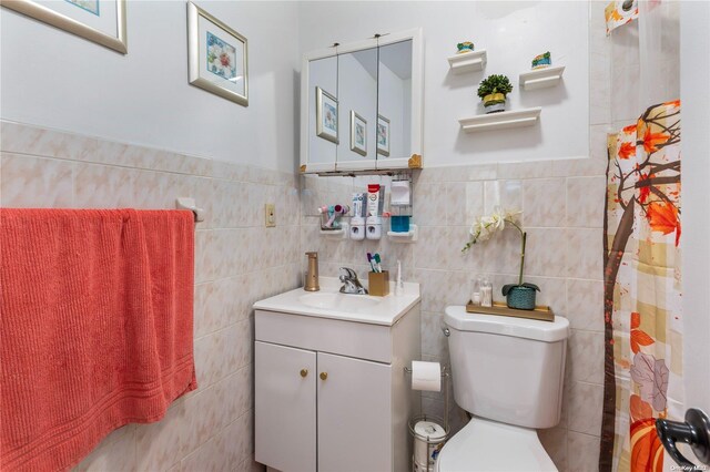 bathroom featuring vanity, toilet, and tile walls