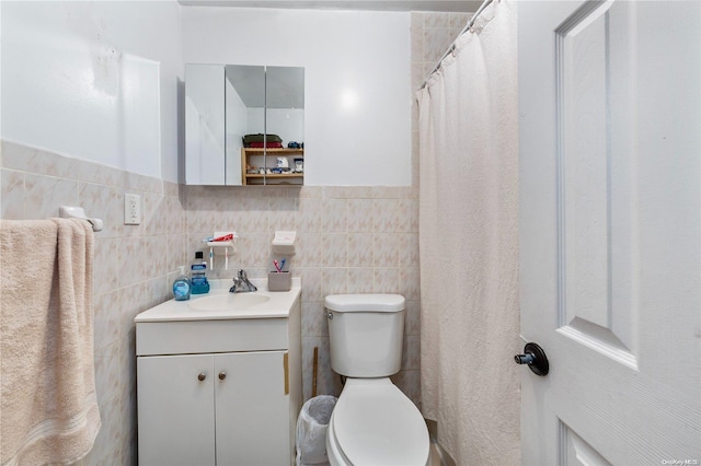 bathroom with curtained shower, vanity, tile walls, and toilet