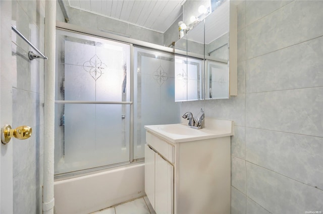 bathroom with vanity, tile walls, and enclosed tub / shower combo