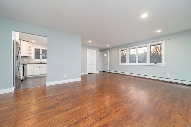 unfurnished living room featuring baseboard heating and dark hardwood / wood-style floors