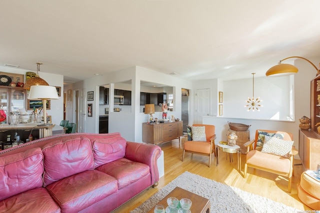 living room featuring a notable chandelier and light wood-type flooring