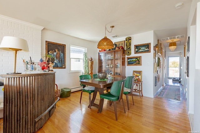 dining space featuring light wood-type flooring, baseboard heating, and a wealth of natural light