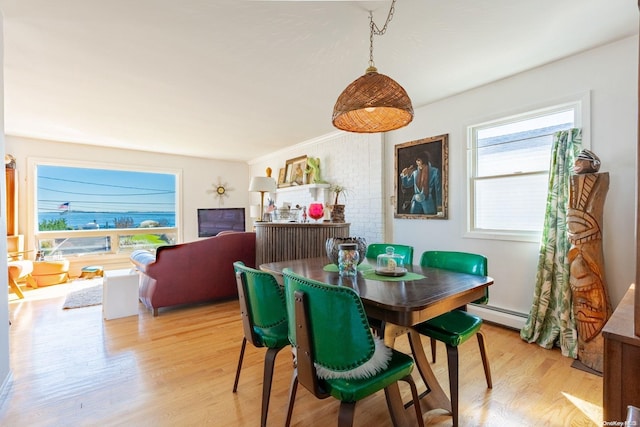 dining area with crown molding, light hardwood / wood-style floors, and a baseboard heating unit