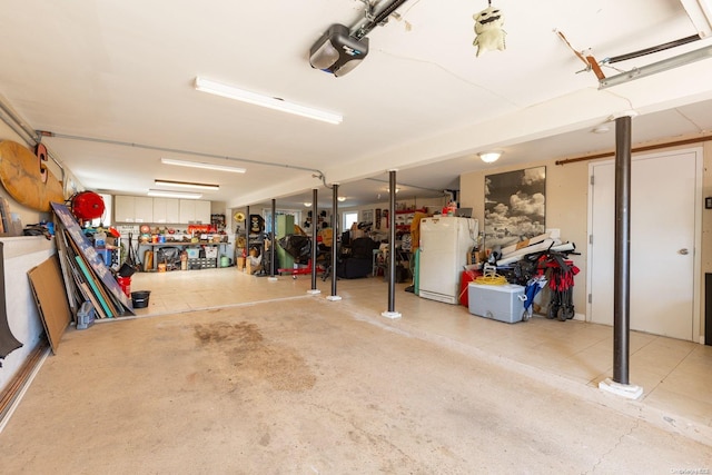 garage featuring a workshop area, white refrigerator, and a garage door opener