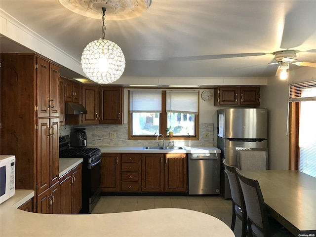 kitchen featuring sink, backsplash, pendant lighting, light tile patterned flooring, and appliances with stainless steel finishes