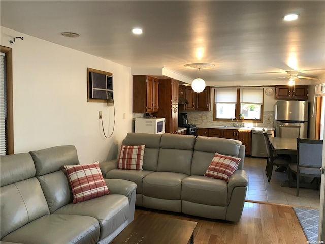 living room with ceiling fan, light hardwood / wood-style floors, sink, and a wall unit AC