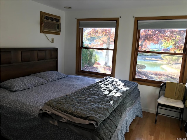 bedroom with a wall mounted air conditioner and hardwood / wood-style flooring