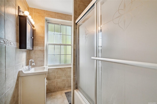 bathroom with tile patterned flooring, vanity, bath / shower combo with glass door, and tile walls