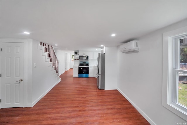 hallway featuring a wall unit AC and light hardwood / wood-style flooring