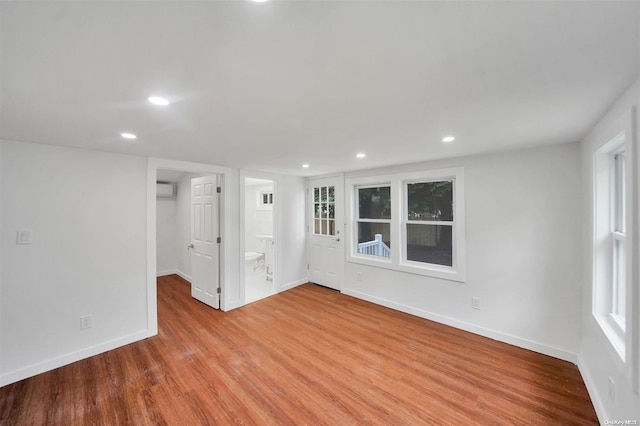 spare room featuring light wood-type flooring and an AC wall unit