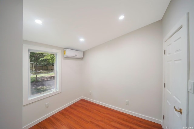 unfurnished room with a wall mounted air conditioner and hardwood / wood-style flooring