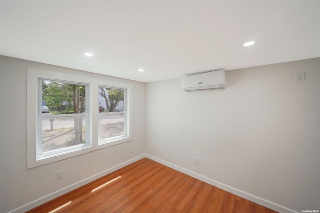 unfurnished room featuring hardwood / wood-style floors and an AC wall unit