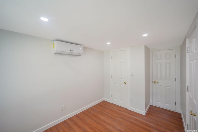 basement with hardwood / wood-style floors and a wall mounted air conditioner