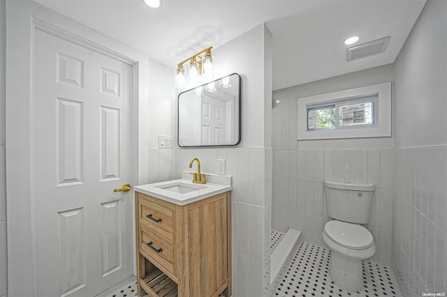 bathroom featuring vanity, toilet, tile walls, and walk in shower