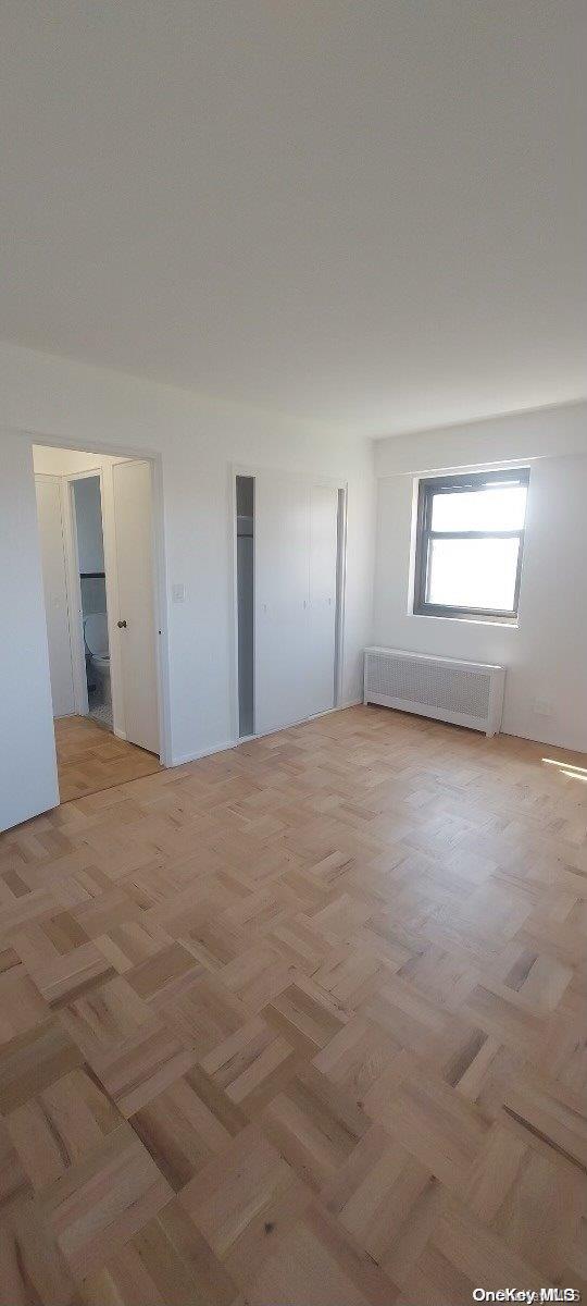 empty room featuring radiator heating unit and light parquet floors