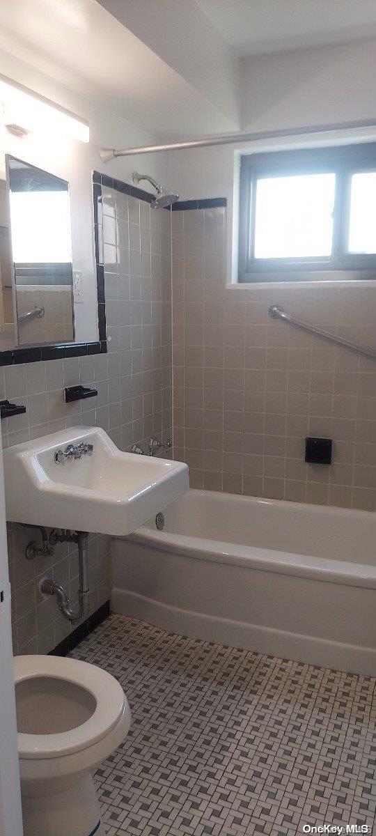 full bathroom with sink, tile patterned flooring, tiled shower / bath, and toilet