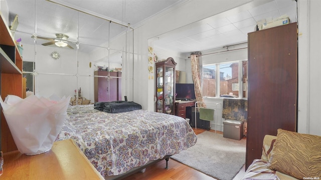 bedroom with hardwood / wood-style flooring, ceiling fan, and ornamental molding