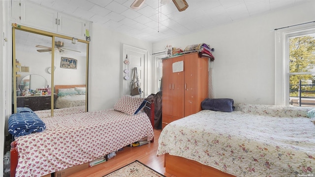 bedroom featuring hardwood / wood-style floors, ceiling fan, a closet, and multiple windows